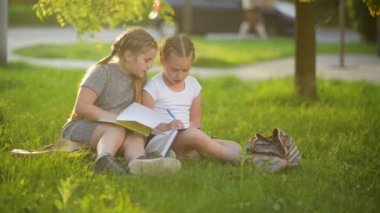 Bir kitap yaz bahçesinde çocuklar. Okul öncesi oyun arkadaşları ve öğrenme. Ödevlerini yapıyor kızlar.