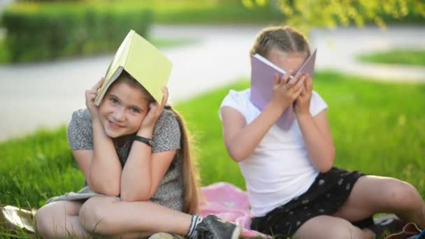 Két vicces lány játszik könyvek. Ők mosolyogva és birtoklás sok móka. Az időjárás is napos. — Stock videók