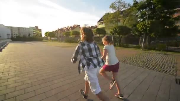 Menino e menina correm juntos segurando as mãos no asfalto. Eles têm um monte de diversão . — Vídeo de Stock