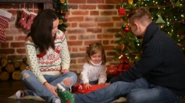Aile şömine, Noel arifesinde. Anne ve küçük çocuk Noel hediyeleri açma. Hediye kutuları çocuklarla. Geleneksel şömine ve dekore edilmiş ağaç oturma odası. Sıcacık kış akşam evde.