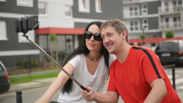 愛情のあるカップルは市内中心部で、スマート フォンで、Selfie を取っています。彼らはお互いを保持してカメラを見ています。. — ストック動画