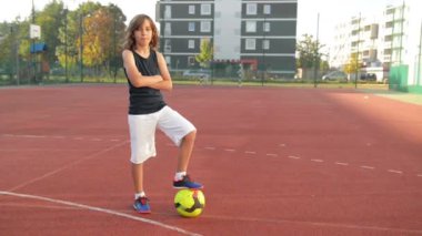 Spor çocuk poz. Futbol topu tutuyor. Çocuğun iyi bir ruh hali var. Evlat, gülümse, açık havada, aktif.