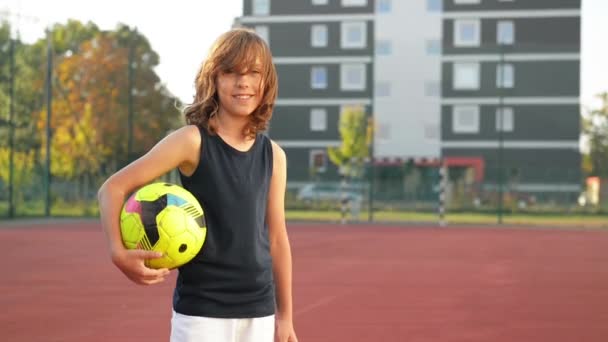 サッカー ボールの少年の肖像画。スポーツの概念。彼はサッカーを再生する楽しみの多くを持っています。. — ストック動画