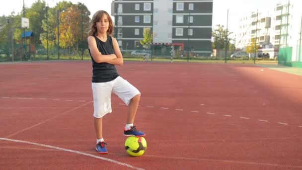 Sportjunge posiert. Er hält Fußball. Der Junge hat gute Laune. Kind, Lächeln, im Freien, aktiv. — Stockvideo