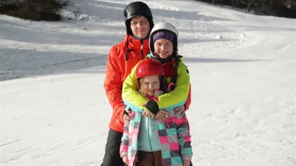 Familia joven feliz en traje de esquí con niños divertidos en ropa de invierno brillante. Caminando con las manos en el parque. Maravillosas vacaciones de invierno para toda la familia . — Vídeos de Stock