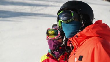 Genç bir çift karlı Resort portresi. Kar gözlükleri ve kask takarlar.