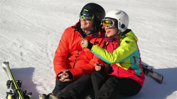 Paar skiërs plezier, zittend op een sneeuw. Ze hebben goed humeur deze tijd samen doorbrengen. — Stockvideo