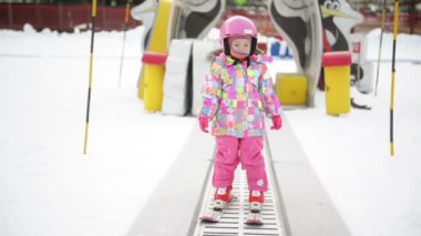 Kış kıyafeti Kayak taşıyıcı üzerinde kalan küçük kız. Çocuk kayak eğlenceli başlar yaşıyor. Mutlu Ski Resort durumumda.