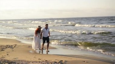 Genç çift sahilde aşık. Güzel çift beyaz giysili. Aşıklar el ele tutuşarak ve sarılma.