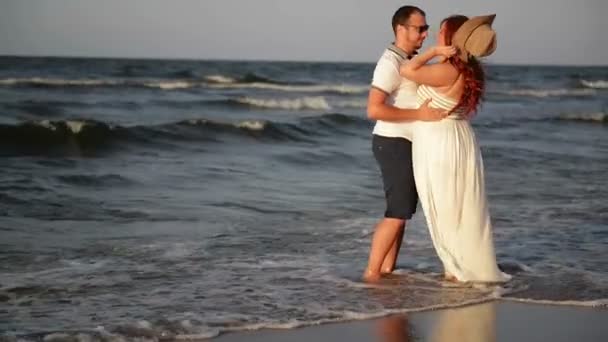 Genç çift sahilde aşık. Güzel çift beyaz giysili. Aşıklar el ele tutuşarak ve sarılma. — Stok video