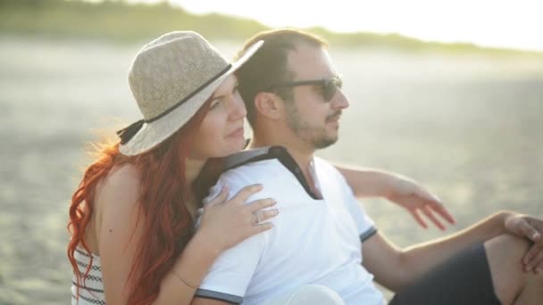 Egy fiatal pár a szerelem pihenés, és élvezi a napfelkeltét a tengerparton. Nekik van egy csomó szórakoztató kiadási dátum együtt. — Stock videók