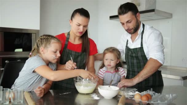 Οικογένεια μαγείρεμα μαζί. Έχουν πολλή διασκέδαση παίζοντας στην κουζίνα. Χαριτωμένο κόρες με τους όμορφος γονείς παίζουν με το αλεύρι. Αυτοί χαμογελαστός κατά το μαγείρεμα. — Αρχείο Βίντεο