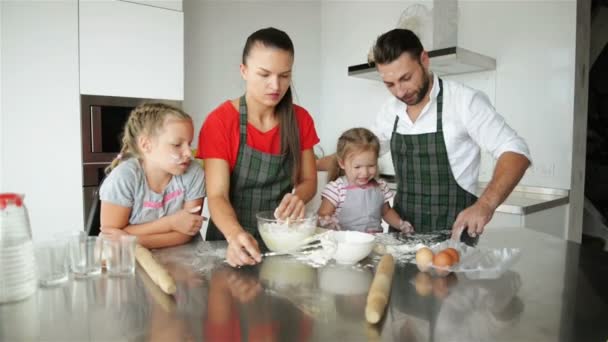 Los padres enseñan a los niños a cocinar. Muestran a los niños cómo cocinar masa . — Vídeos de Stock