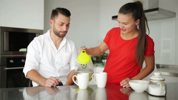 Bonito casal jovem bebendo café na cozinha. Eles têm bom humor esta manhã . — Vídeo de Stock