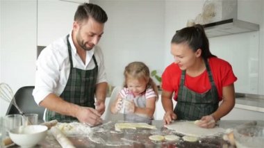 Sevimli küçük kız ve güzel ailesi yemek vardır. Onlar evde mutfak eğlenceli birlikte ve gülümseyen bir sürü var. HD, üç, mutlu bir aile.