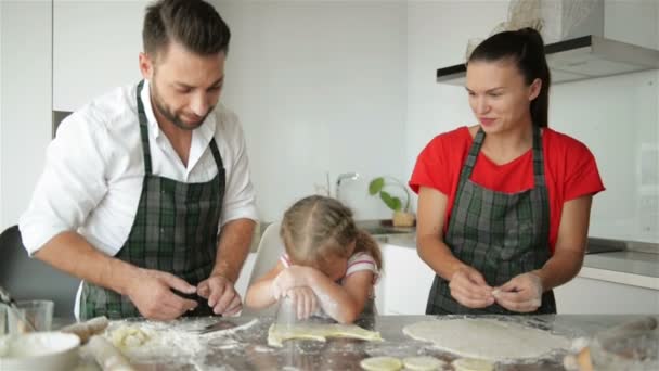 幸せな家族が一緒に料理します。若い娘は、両親に役立っています。彼らは楽しいのたくさんをあります。. — ストック動画