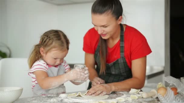 La pequeña partidaria está ayudando a su madre a cocinar. Madre muestra a su hija cómo preparar la masa . — Vídeos de Stock