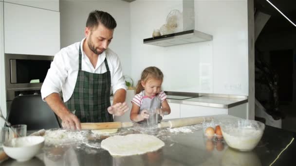 Дочь помогает отцу готовить еду на кухне. Папа учит ее ребенка готовить муку. . — стоковое видео