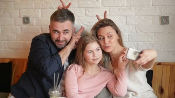 Retrato da família feliz fazendo selfie no Smarthphone interior. Eles passam este belo dia no café . — Vídeo de Stock