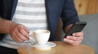 İşadamı kapatın. Kahvaltı sırasında çalışır. Onun Smartphone tutarak ve kahve veya çay içme.