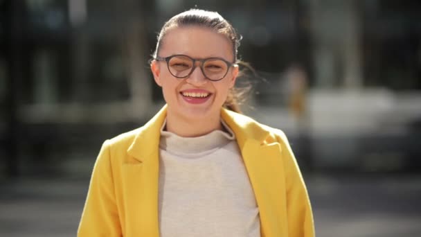 Retrato de una alegre joven mujer de negocios sonriente con un abrigo amarillo. Ella tiene muy buen humor pasar tiempo en una ciudad . — Vídeo de stock