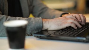 Internet Cafe kapalı dizüstü siting üzerinde Freelancer çalışma yakın görünüm. Genç sakallı adam dizüstü üzerinde düğmeler basarak metin yazıyor. Online Iş, Freelance, ofis.