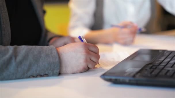 Dos empresarios se reúnen alrededor de una mesa de madera en aan Office. El hombre está escribiendo texto en papel . — Vídeos de Stock