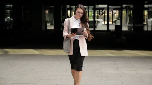 Jonge succesvolle brunette zakelijke vrouw loopt door de stad met documenten en het tellen van papieren. — Stockvideo