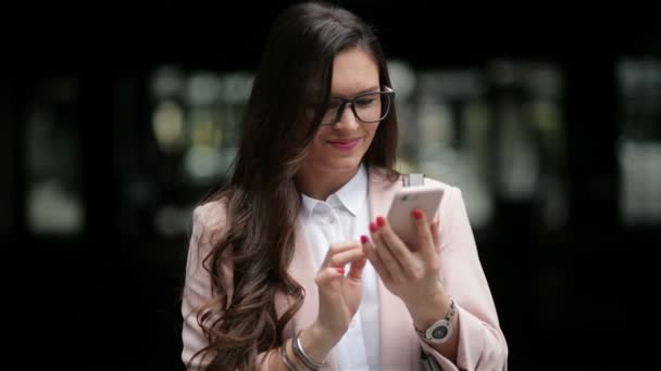 Счастливая деловая женщина пользуется смартфоном, стоящим на улице. Она получает хорошие новости. Телефонный разговор — стоковое видео