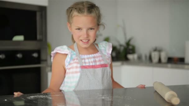 작고 귀여운 소녀가 부엌에서 요리를 하고 있습니다. 케이크랑 쿠키만들면서 재밌게 놀고 있어. 웃고 카메라를 보는 모습. — 비디오