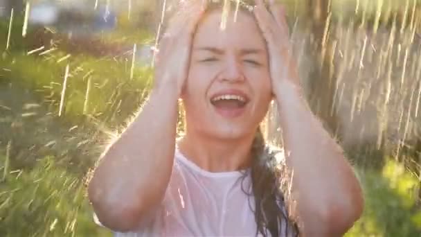 La jeune femme sourit et rit sous la pluie. Les gouttes de pluie tombent sur son visage et elle est heureuse avec la vie et la nature autour. Concept de Nature et Vie Heureuse, Aventure, Pureté — Video