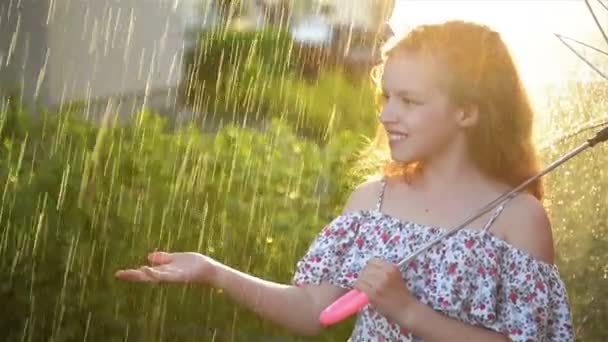 Ένα νεαρό κορίτσι που παίζει στη βροχή με την ομπρέλα. Γλυκό παιδί που διασκεδάζει έξω. — Αρχείο Βίντεο