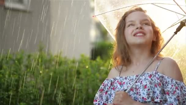 傘を差して雨の中で遊ぶ少女。かわいい子供は楽しい屋外を持っています. — ストック動画