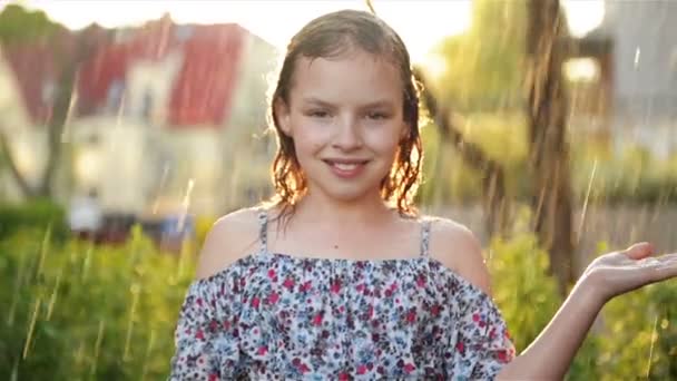 Portait of Adorable Little Girl. Ela está jogando alegremente na chuva no quente dia de verão . — Vídeo de Stock