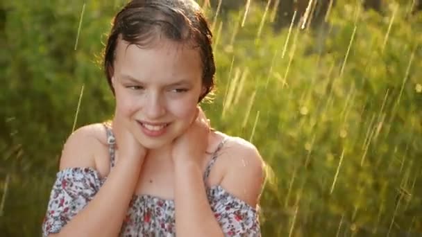 사랑스러운 어린 소녀의 포르타이트. 그녀는 따뜻한 여름 날에 비에 행복하게 놀고있다.. — 비디오
