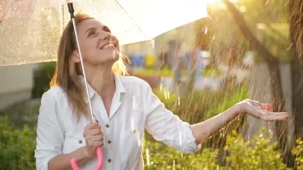 Neşeli kız holding şemsiye ve alıcı yağmur portre kadar bel gülümseme ile bırakır. O el germe ve yukarı doğru samimi sevinçle arıyorsunuz. — Stok video