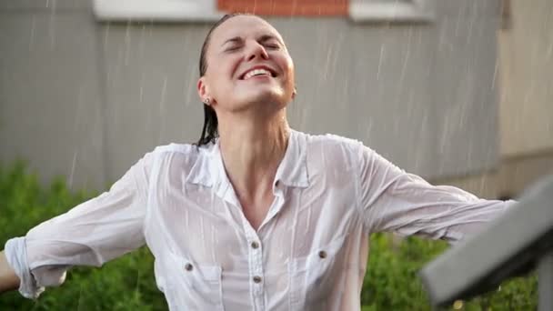 Χαρούμενη νεαρή χαμογελαστή γυναίκα που διασκεδάζει σε βροχερό καιρό. Χαρούμενο κυρία έχει βρεγμένα μαλλιά στο καλοκαιρινό πάρκο. — Αρχείο Βίντεο