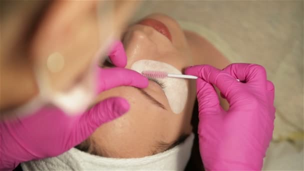 Concepto de maquillaje. El Maestro de la Extensión de Pestañas en Guantes Rosa alarga las pestañas Cliente. Hermosa chica aumenta las pestañas, Primer plano . — Vídeo de stock