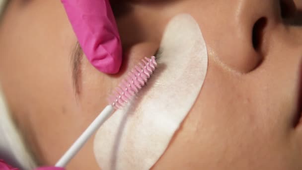 Concetto di trucco. Il Master of Eyelash Extension in Pink Gloves allunga il cliente delle ciglia. Bella ragazza aumenta le ciglia, Primo piano . — Video Stock