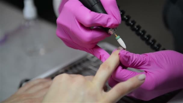 Una mano de manicura con clavos se encuentra en la mano de una manicurista en un guante higiénico rosa. Maestro hace manicura francesa clásica . — Vídeo de stock