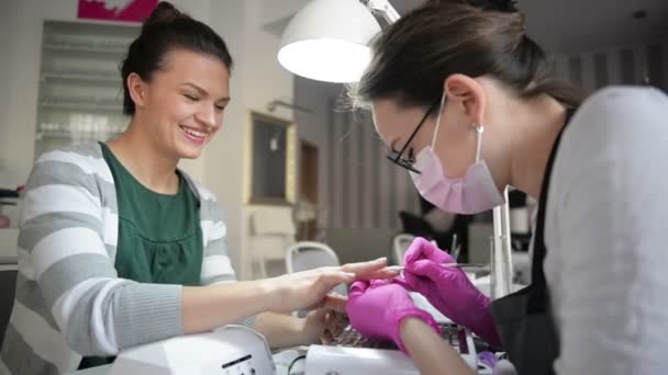 Närbild hårdvara manikyr i en skönhetssalong. Manicurist använda elektrisk nagelfil borra till manikyr på kvinnliga fingrar. — Stockvideo