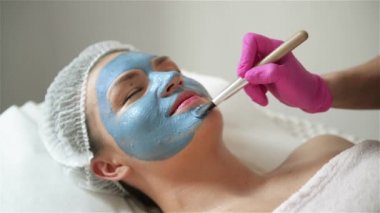 Kozmetolojist Cildin Temizlenmesi ve Nemlandırılması Prosedürü Yapar. Kadının Yüzüne Özel Fırça ile Maske Uygulama. Genç kız cildine dikkat ediyor. Kozmetoloji Kliniği'ni ziyaret edin. Aetetik Tıp.