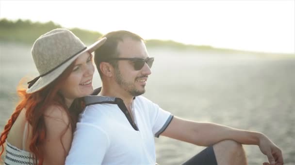 Una joven pareja enamorada está descansando y disfrutando del amanecer en la playa. Tienen un montón de diversión pasar juntos la fecha . — Vídeos de Stock