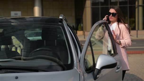 Güzel İş Kadını Cep Telefonu konuşuyor ve onun yeni araba içine otururken gülümsüyor. Sonra bilek saatine bakıyor.. — Stok video