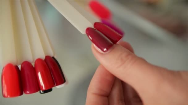 Mano de cámara lenta eligiendo muestras de uñas. Conjunto de cerca de la colección multicolor probadores de color de uñas artificiales y mano de mujer con hermosa manicura . — Vídeos de Stock