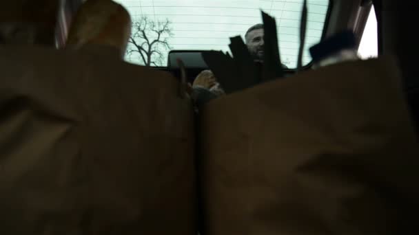 Car pohled na rodinu vykládka potravin sáčky z kufru auta. — Stock video