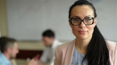 Çalışanlarıyla birlikte çalışan bir iş kadını, modern aydınlık ofiste arka planda çalışan insanlar.