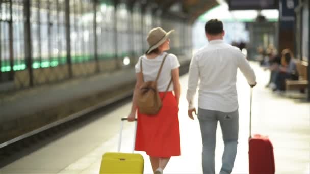Щаслива молода пара їде з багажем біля аеропорту або залізничного вокзалу. Концепція подорожей, відпусток, відпусток. Літній час, захід сонця . — стокове відео