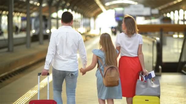 Junge Familie mit süßer Tochter, die mit Koffer auf dem Bahnsteig spaziert. Bestes Reise- und Urlaubskonzept. Kaukasisches Aussehen. — Stockvideo