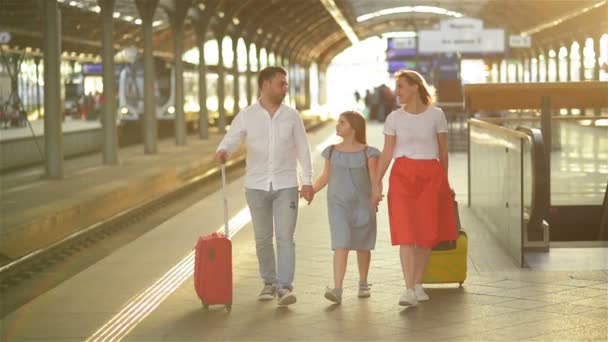 Giovane coppia con figlia Arrivi dalle vacanze. Family Walking sulla piattaforma della stazione ferroviaria con valigie. Gente felice e di buon umore. Insieme. . — Video Stock